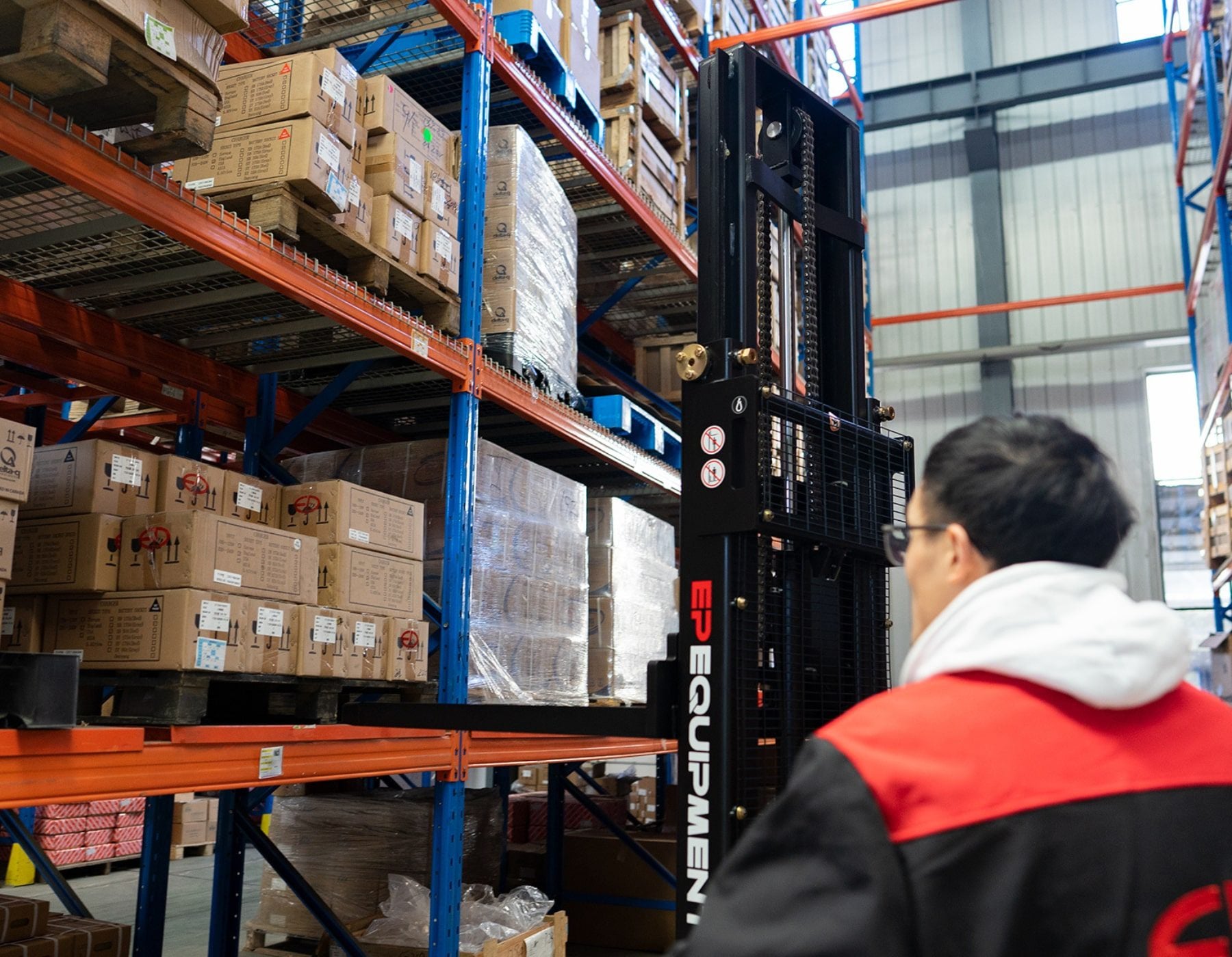 Front angled view of a red and black EP ESl122 electric stacker truck, featuring tall lifting masts and a compact handle design, positioned on a white background
