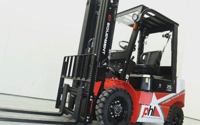 A red and black forklift is parked in a warehouse setting, featuring a raised mast and two front forks for lifting loads.