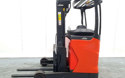 Red and black Linde electric reach truck with forks, photographed indoors against a white wall.