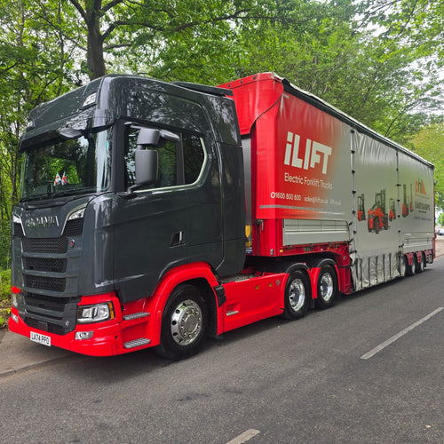 Red and black truck with 'iLIFT' branding on a road surrounded by trees