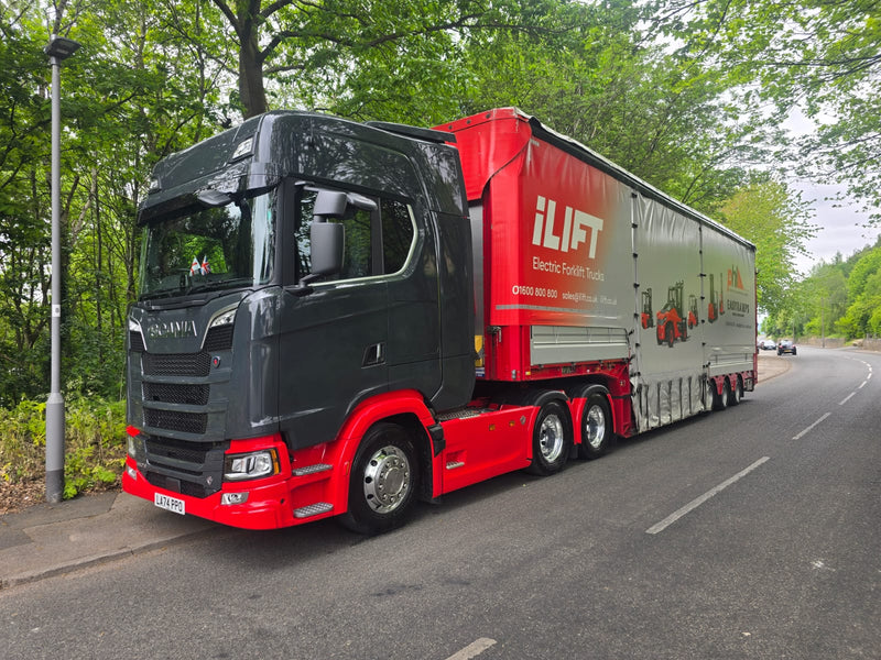 Red and black truck with 'iLIFT' branding on a road surrounded by trees
