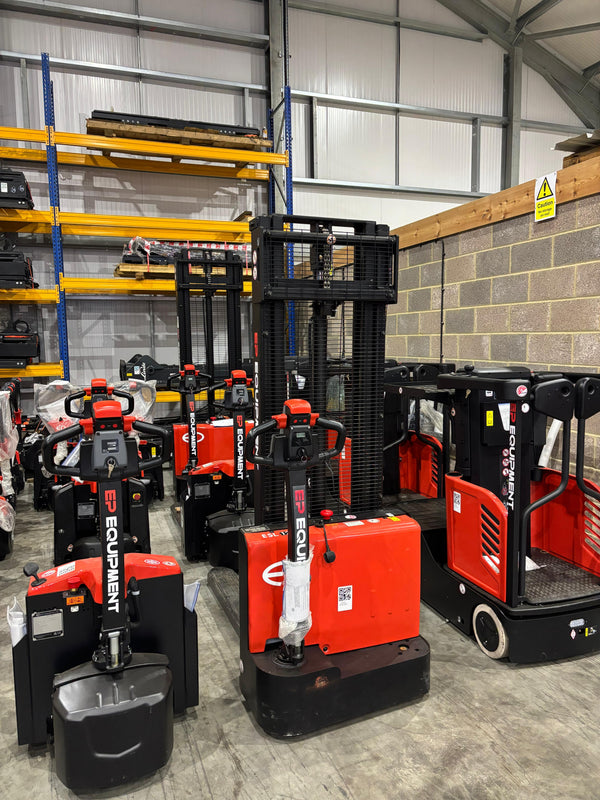 Red and black forklifts in a warehouse setting with shelves and concrete walls.