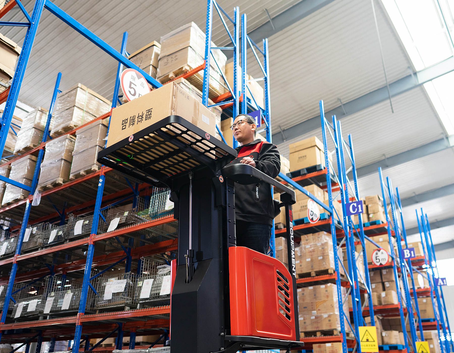 Front angled view of a red and black EP ESl122 electric stacker truck, featuring tall lifting masts and a compact handle design, positioned on a white background